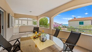 Un balcon avec une table ronde, des chaises et un verre de jus d’orange.