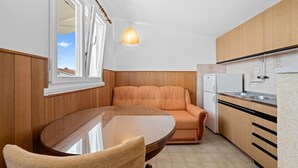 Une cuisine compacte avec un coin repas, un lambris en bois, un réfrigérateur blanc et un luminaire suspendu.