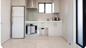Una cocina moderna con armarios blancos, un refrigerador de acero inoxidable, un horno y una ventana sobre el fregadero.
