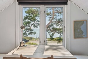 Une piÚce avec vue sur la mer, une table, une lampe et une carte accrochée au mur.