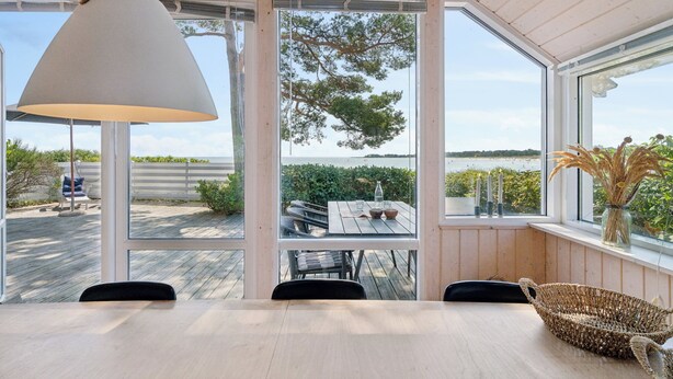 Un espace repas comprenant une table, des chaises, une lampe suspendue et une vue sur l’extérieur.