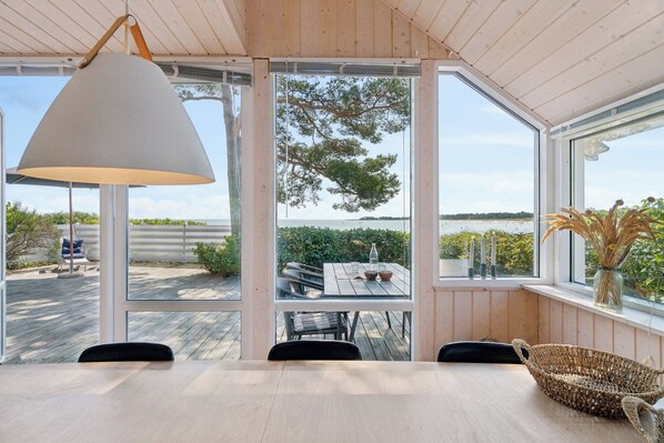 Un espace repas comprenant une table, des chaises, une lampe suspendue et une vue sur lâextĂ©rieur.