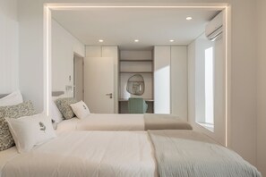 A modern bedroom with a large bed, a desk, and a wardrobe.