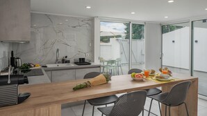 A modern kitchen with a marble backsplash, a wooden dining table, and a view of the outdoors.
