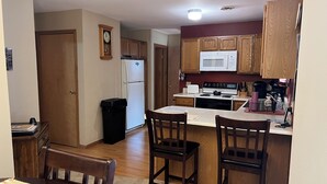 Una cocina compacta con armarios de madera, microondas, estufa y un cubo de basura.