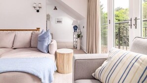 A bedroom with a bed, a sofa, a round side table, and a window with curtains.