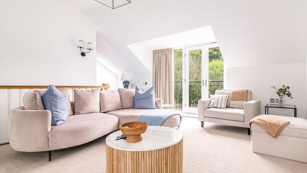 A modern living room with a curved sofa, a round wooden coffee table, and a separate armchair.