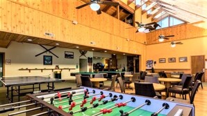 A spacious indoor area with a foosball table, multiple seating arrangements, and ceiling fans. - Getaways at Lagonita Lodge (Big Bear Lake)