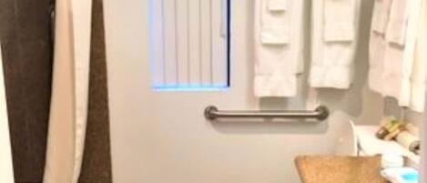 A bathroom with a toilet, a sink, a shower, and a window.
