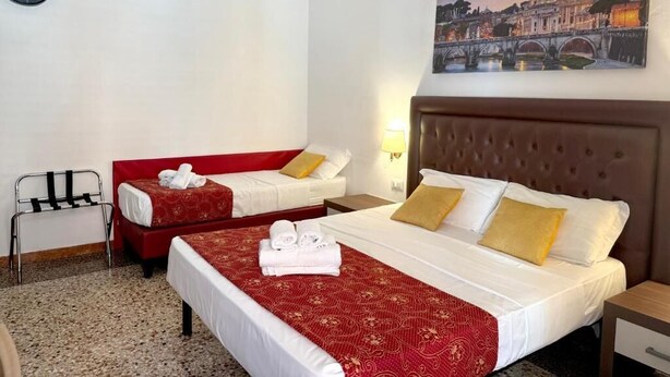 A hotel room with two beds, a red sofa, a clock, and a painting of a cityscape. - Grand Gaeta  (Rome)