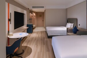 Una habitación de hotel con dos camas, un escritorio, una silla y un televisor.