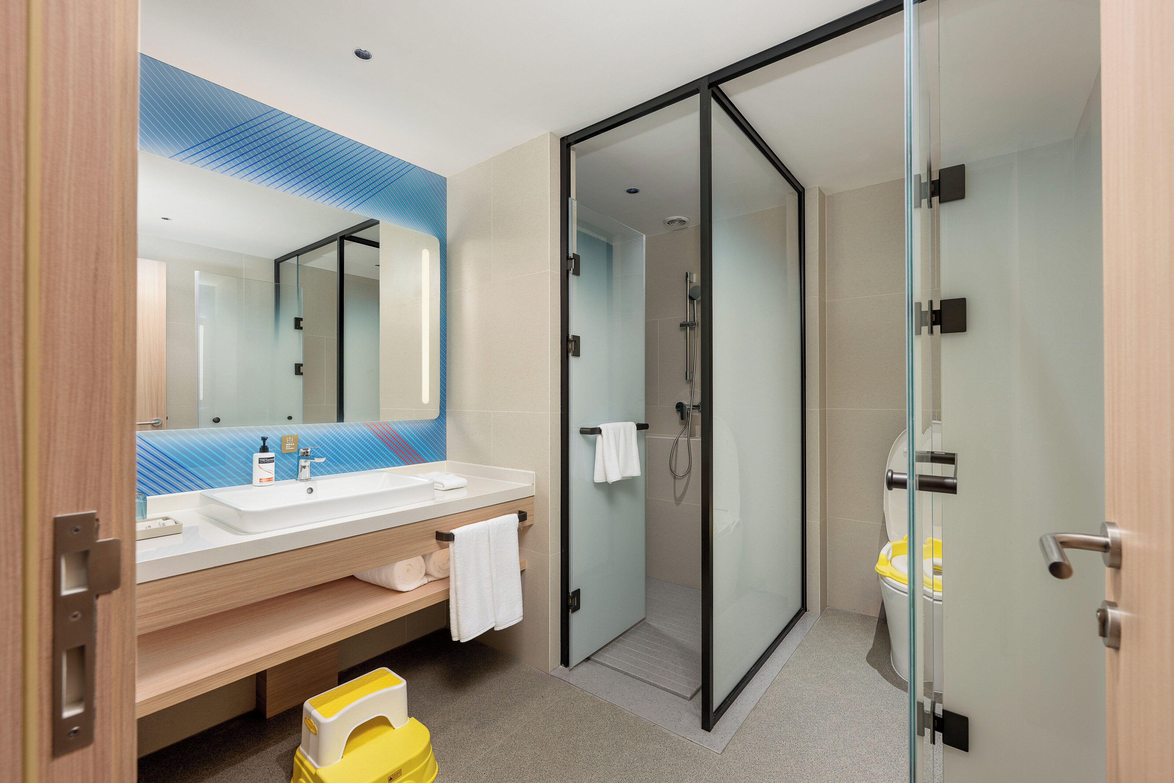 Un bagno moderno con cabina doccia in vetro, un lavabo con specchio e un mobile vanitario in legno.