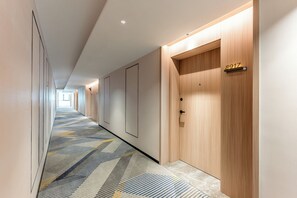 A hotel hallway with a patterned carpet, wooden doors, and a number sign. - Holiday Inn Express Jincheng New District (Jincheng)