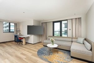 Una sala de estar moderna con un sofá, una pequeña mesa redonda, un televisor y un escritorio con una silla.