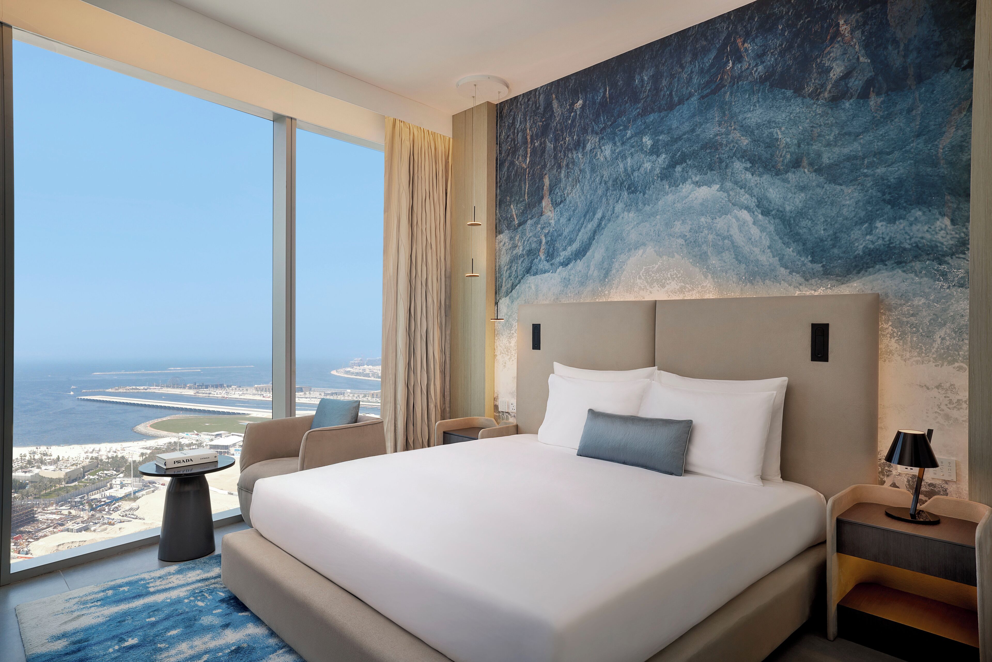 A hotel room with a large bed, a view of the ocean, and a modern design.