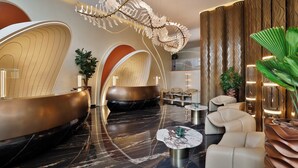 Eine moderne Lobby mit einer gebogenen Rezeption, Sitzbereichen und einer außergewöhnlichen Deckenleuchte.