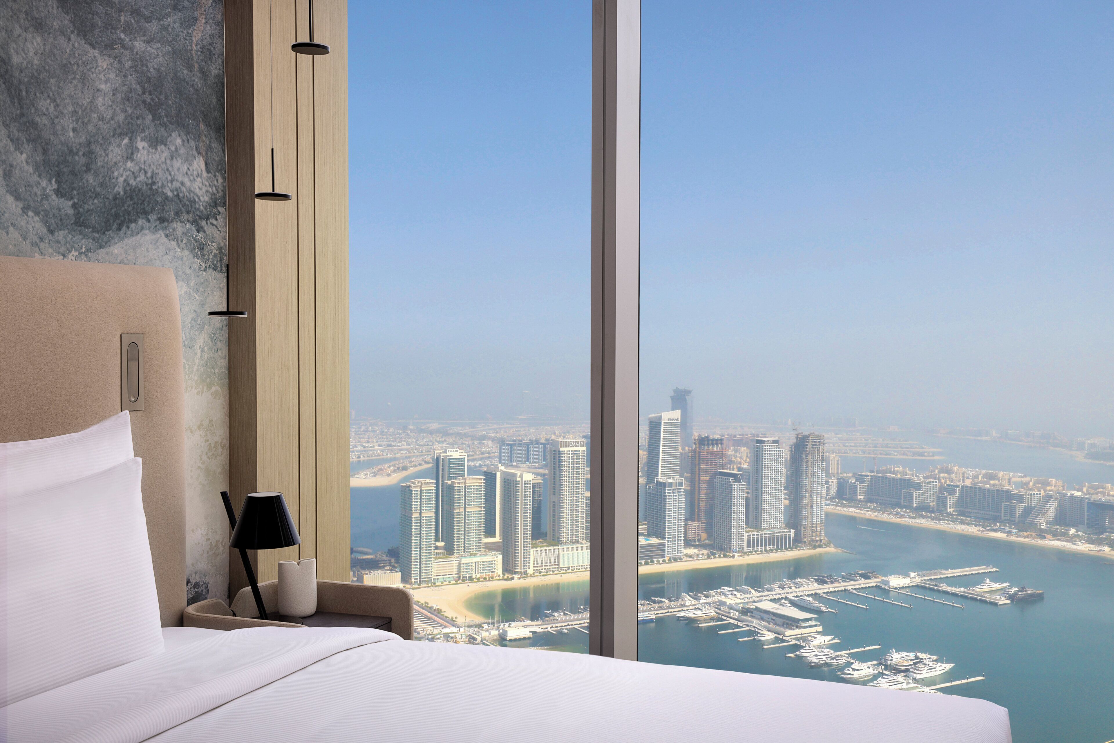 Ein Hotelzimmer mit großem Fenster und Blick auf Stadtlandschaft und Hafen.