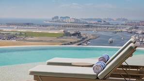 A poolside lounge with a view of a marina and distant buildings. - Ciel Dubai Marina, Vignette Collection by IHG (Dubai)