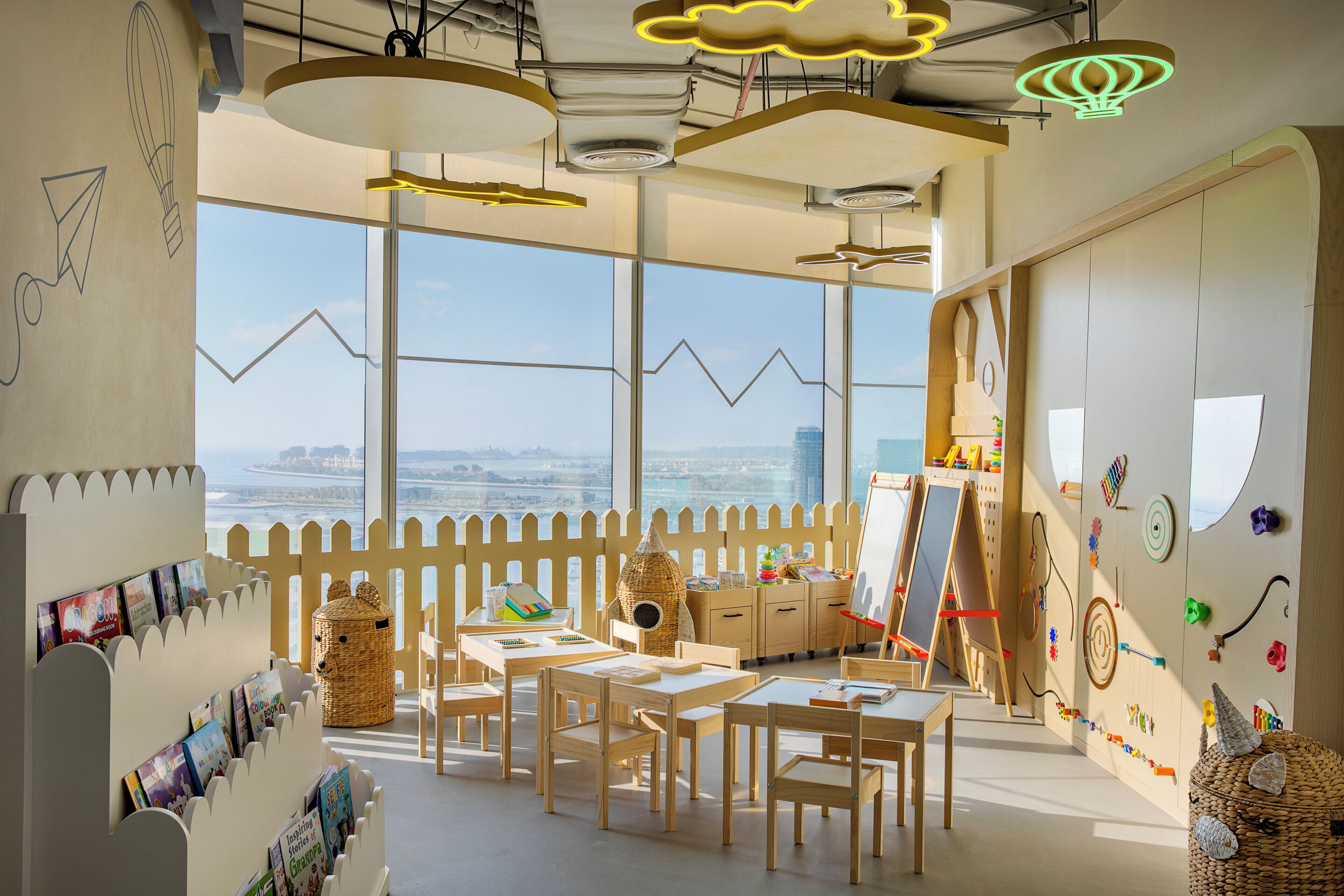 A classroom with large windows, a white picket fence, and educational materials.