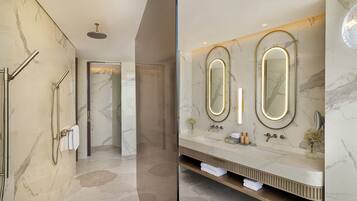 A modern bathroom with a marble floor, a walk-in shower, and a vanity with two mirrors and a sink.