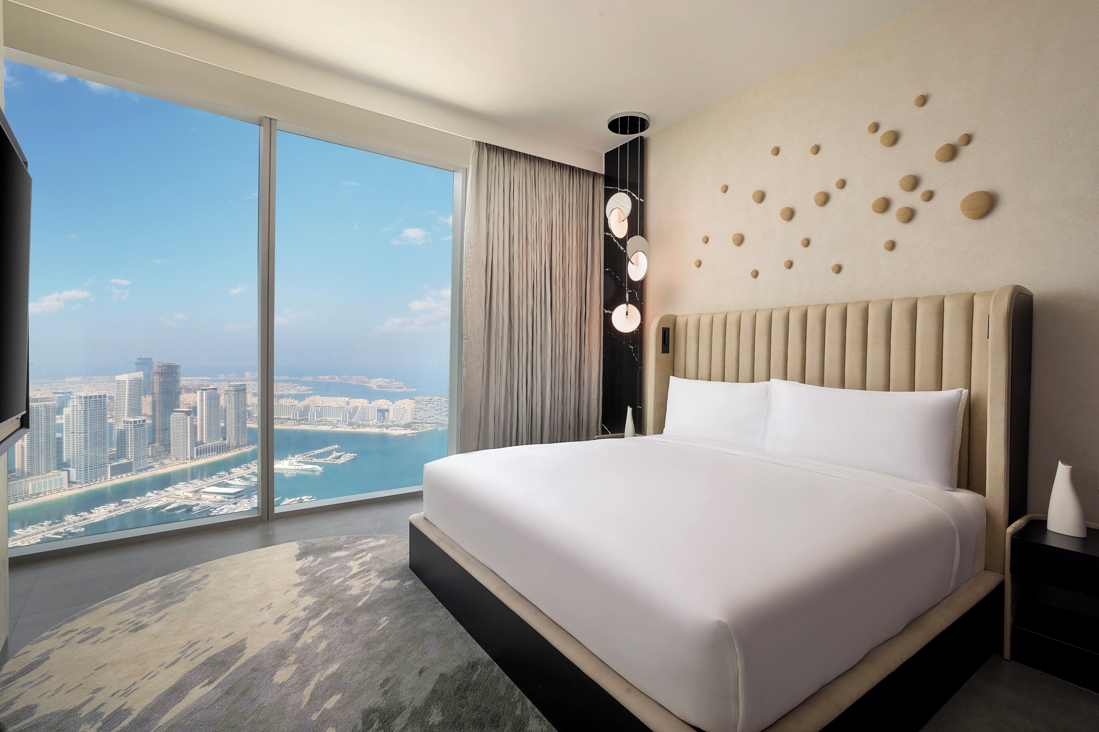 Ein modernes Hotelzimmer mit großem Bett, Blick auf die Stadt und einzigartiger Wandgestaltung.