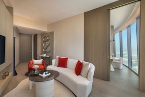 A modern living room with a curved sofa, a glass coffee table, and a view of the sea through large windows. - Ciel Dubai Marina, Vignette Collection by IHG (Dubai)