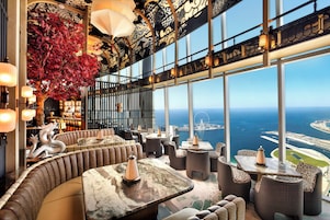 Un interior lujoso con una zona de estar curva, un amplio ventanal con vistas al mar y un techo decorativo.
