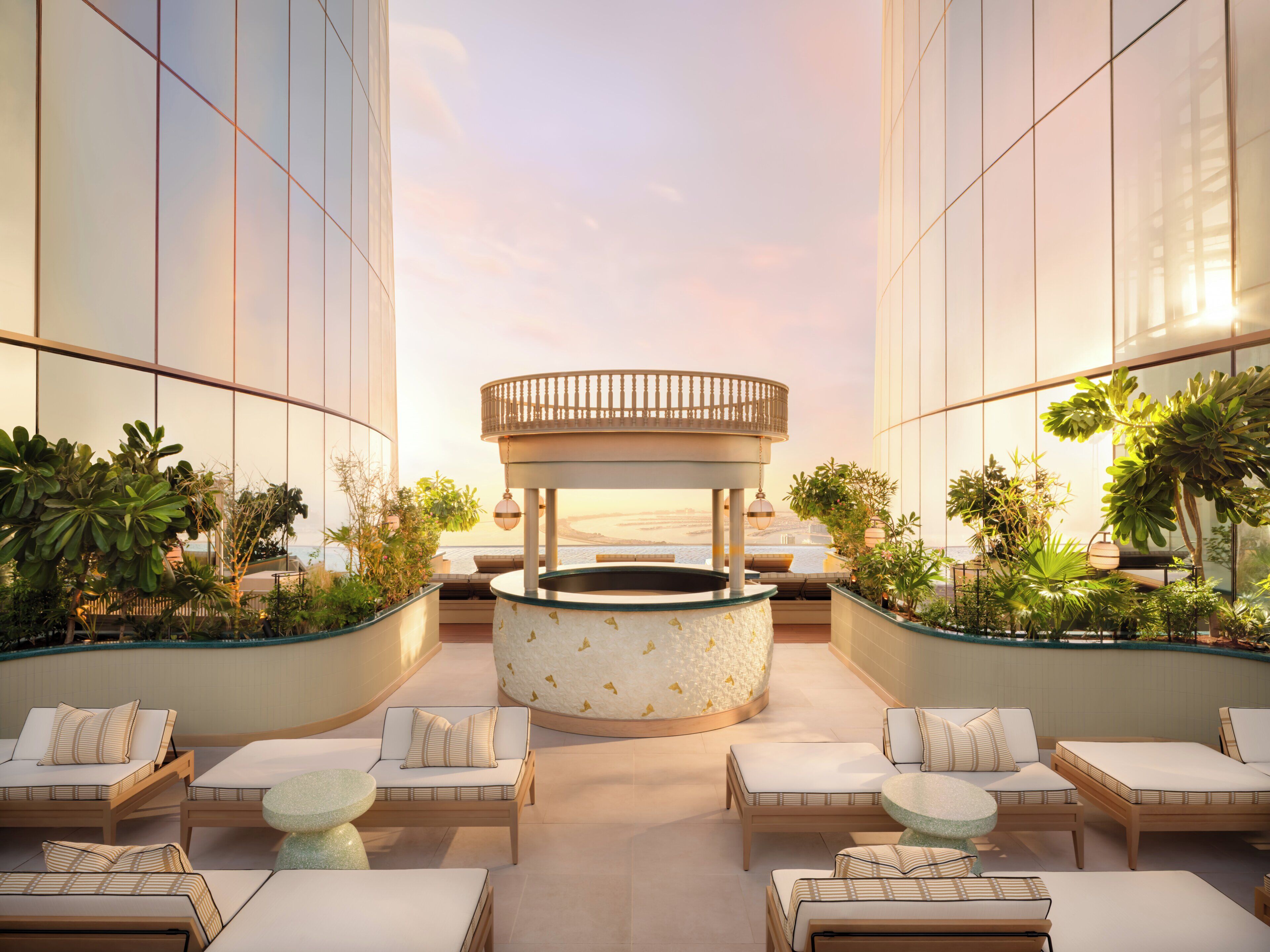 A modern rooftop lounge with a central circular seating area, surrounded by lounge chairs and planters.