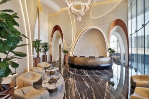 A modern lobby with a seating area, a reception desk, and a large arched window. - Ciel Dubai Marina, Vignette Collection by IHG (Dubai)