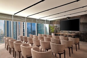 A conference room with a large screen, multiple chairs, and a city view.