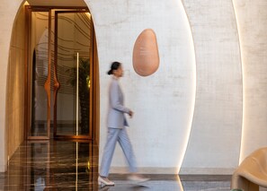 A modern building entrance with a glass door, a curved wall, and a sign indicating an elevator lobby. - Ciel Dubai Marina, Vignette Collection by IHG (Dubai)