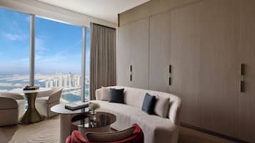 A modern living room with a sofa, a coffee table, and a view of a cityscape through large windows.
