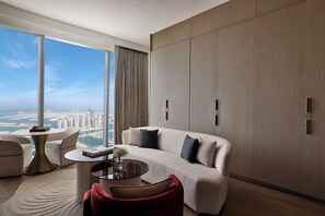 Una sala de estar moderna con un sofá, una mesa de centro y vistas a un paisaje urbano a través de grandes ventanales.