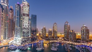 A marina with numerous yachts docked, surrounded by high-rise buildings with illuminated windows. - Ciel Dubai Marina, Vignette Collection by IHG (Dubai)