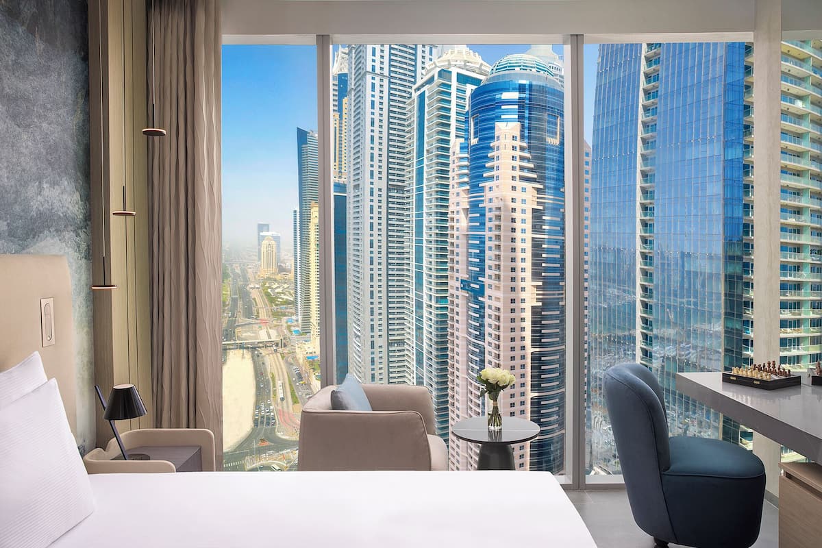 A modern hotel room with a large window offering a view of high-rise buildings.