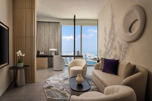 Ein modernes Wohnzimmer mit Sofa, Sessel und Couchtisch, einem Flachbildfernseher und einem großen Fenster mit Blick auf die Stadt.
