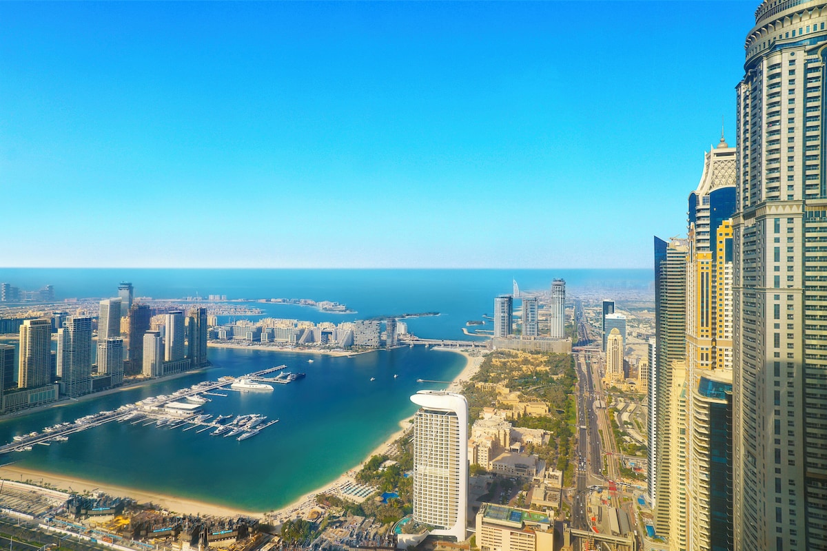 Ein Hochhaus-Hotel mit Blick auf einen Yachthafen, einen Strand und eine Stadtansicht.