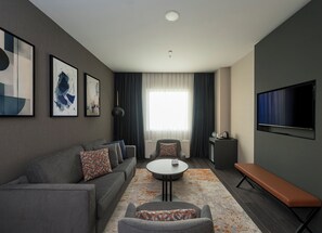 Ein modernes Wohnzimmer mit einer Couch, einem Couchtisch, einer Bank und einem Flachbildfernseher.