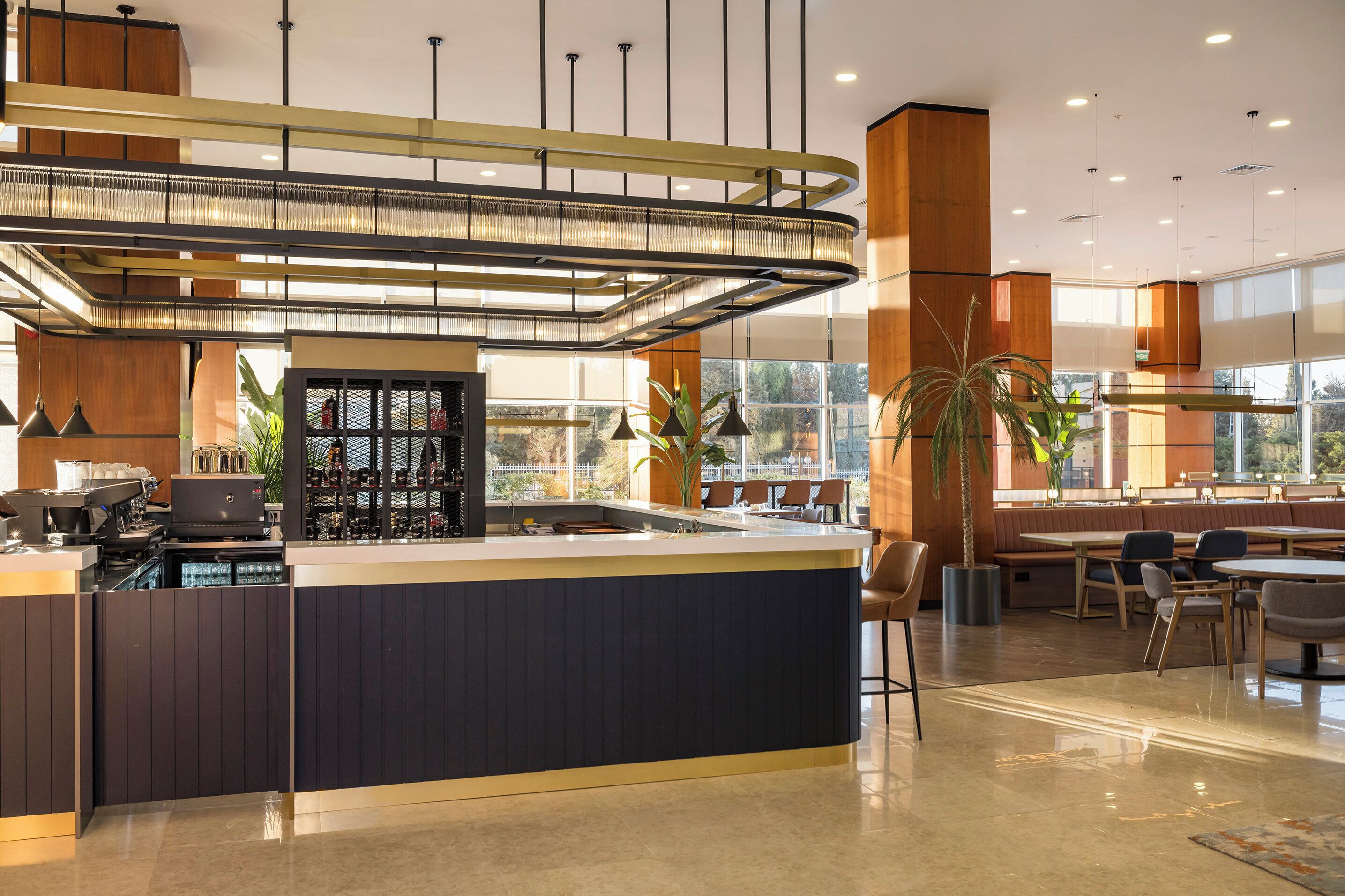 Un espace bar moderne doté d’un îlot central, de sièges et de grandes fenêtres.