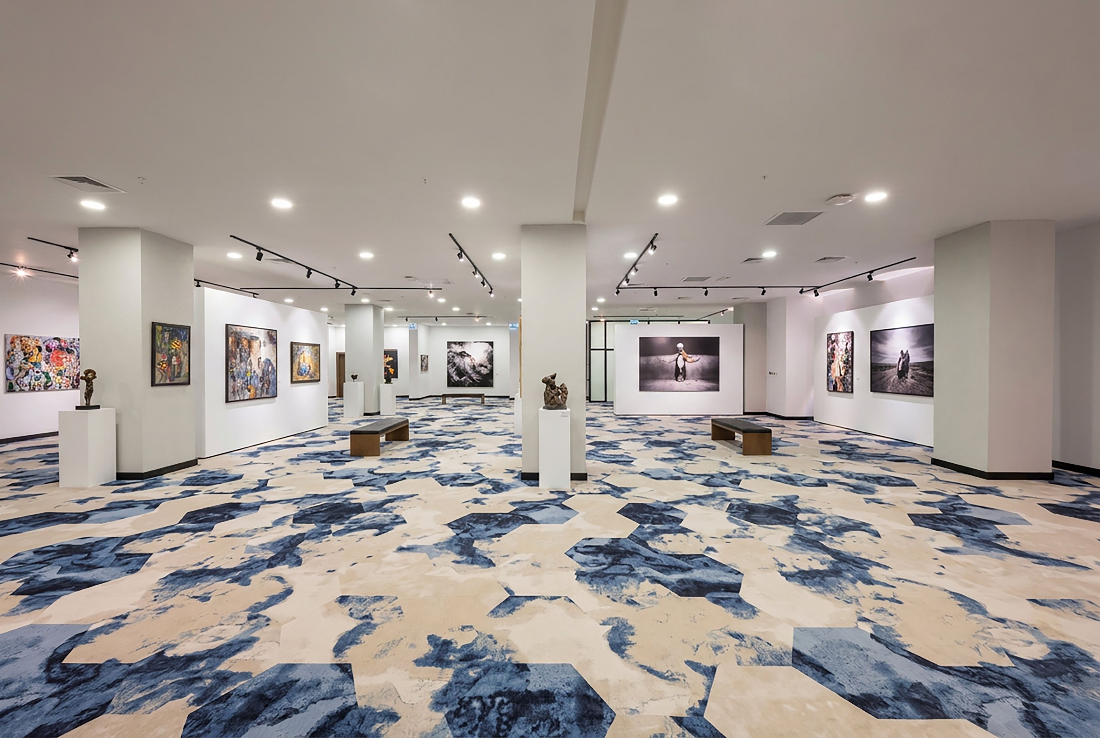 Eine geräumige Kunstgalerie mit einem gemusterten Boden und Deckenleuchten.