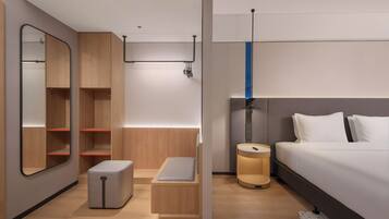 A modern hotel room with a bed, bedside table, nightstand, and built-in wardrobe.