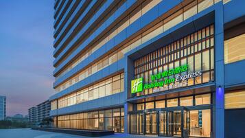 A Holiday Inn Express hotel with a modern facade, large windows, and a prominent green logo.