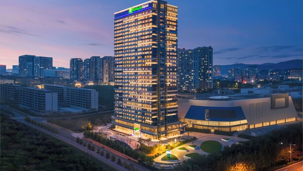 A high-rise hotel with multiple floors, a prominent sign at the top, and a well-lit facade.