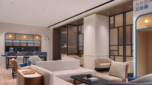 A modern hotel lobby with a seating area, a counter, and a large window.