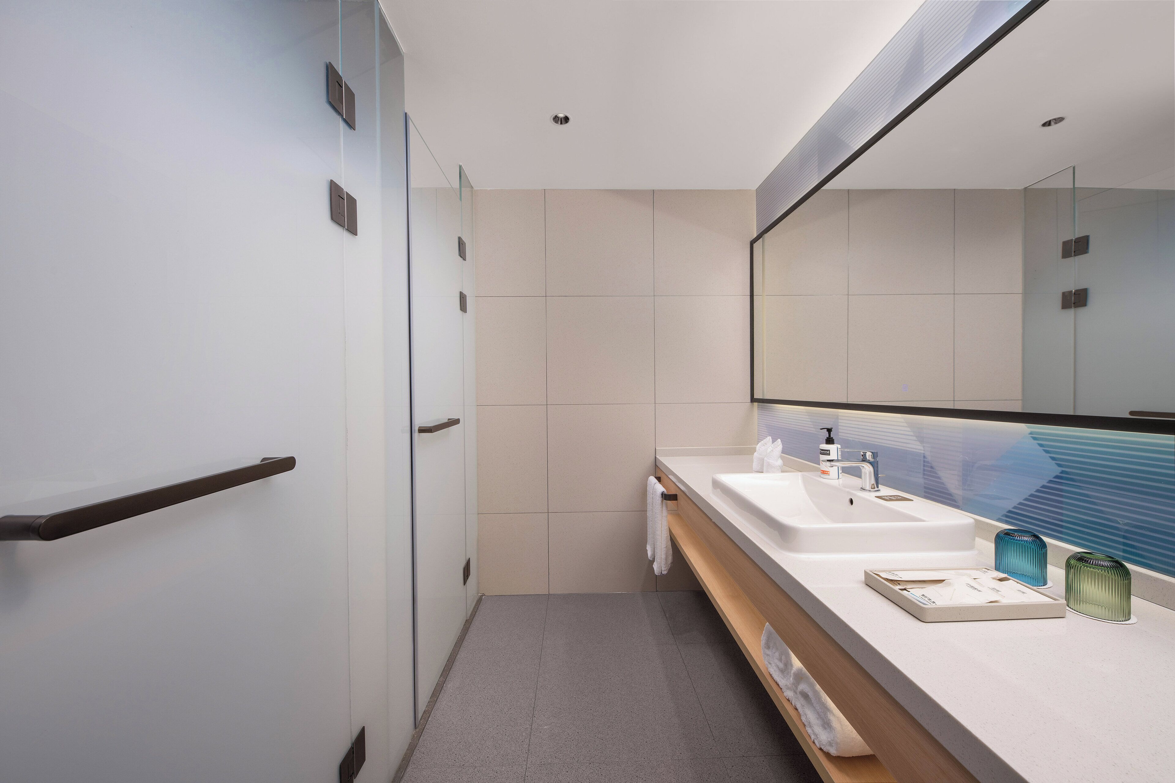 A modern bathroom with a large mirror, two sinks, and a towel rack.