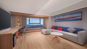 A modern living room with a sofa, a coffee table, a TV, and a city view.