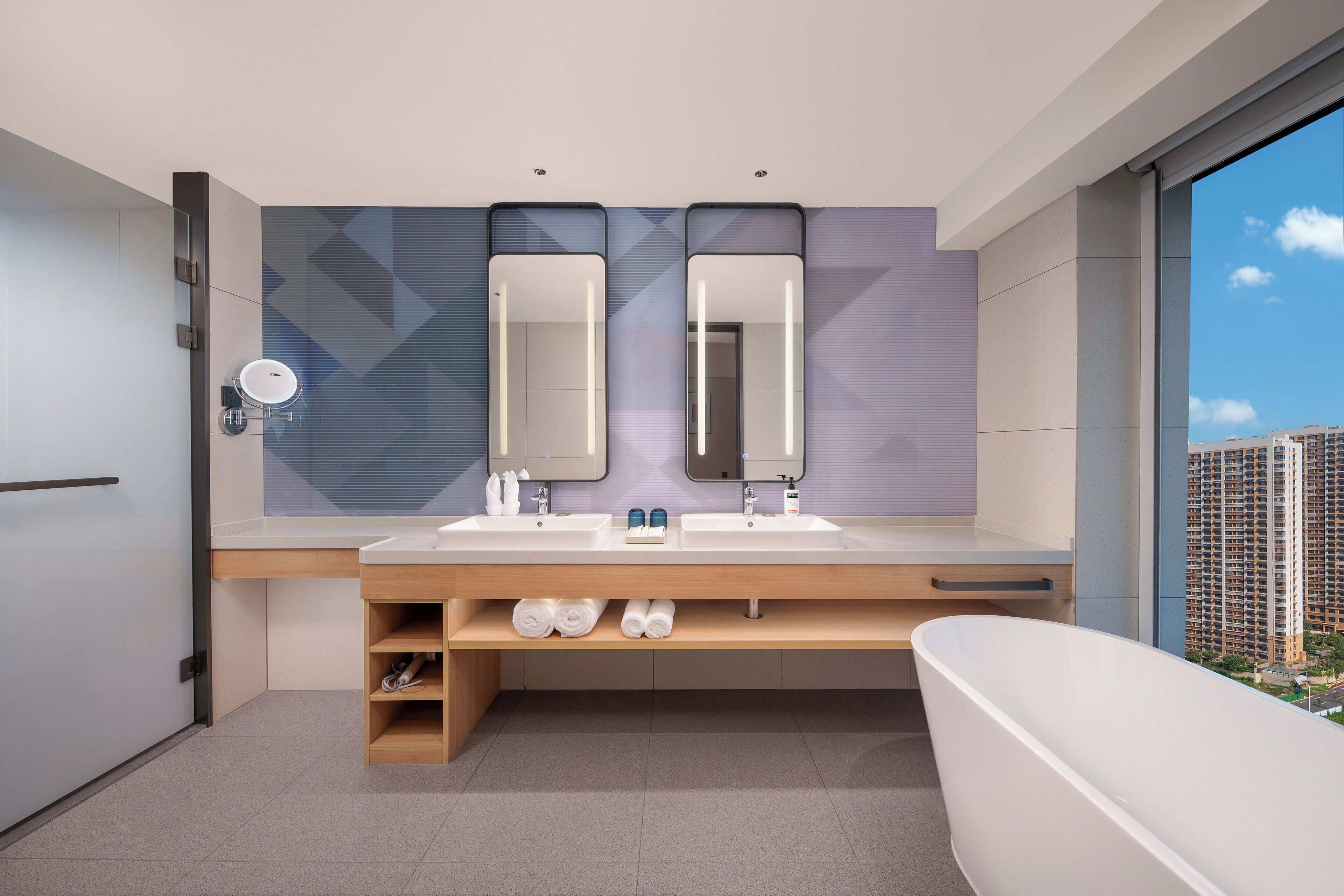 Un baño moderno con tocador doble, un espejo grande y una bañera.