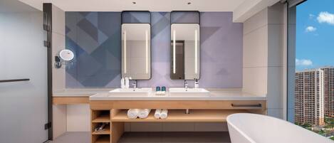 Un baño moderno con tocador doble, un espejo grande y una bañera.
