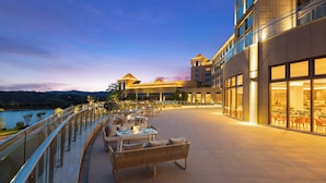 A hotel with outdoor seating, a pool, and a view of the mountains. - Crowne Plaza Xiangyang Fuchun Lakeside by IHG (Xiangyang)