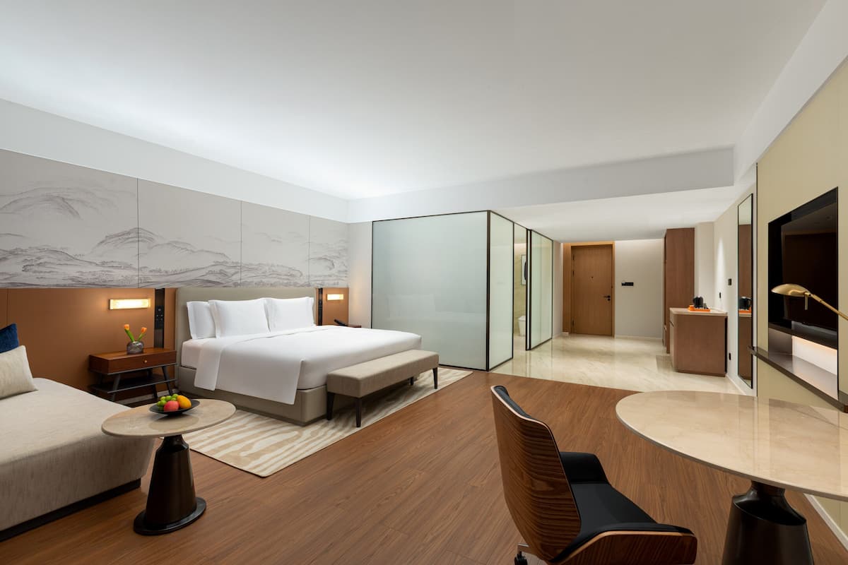 Une chambre d’hôtel moderne équipée d’un lit, d’une table de chevet, d’une chaise et d’un téléviseur.